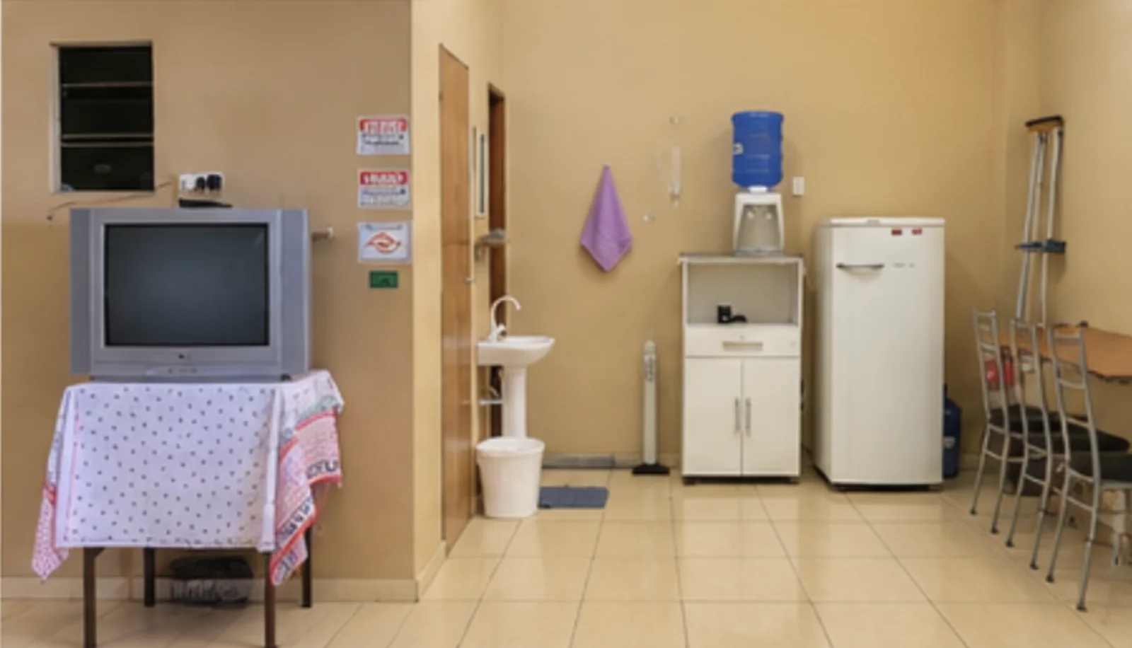 Área de apoio dos hóspedes com TV, bebedouro, geladeira e mesa